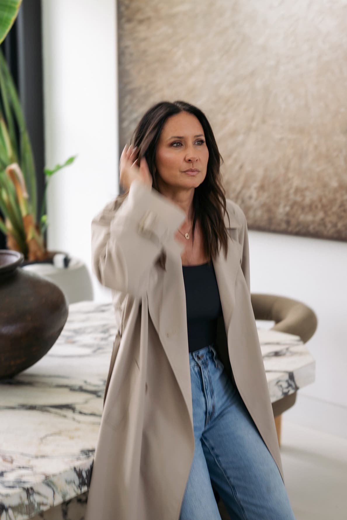 Amy Youngren in a trench coat beside a marble table