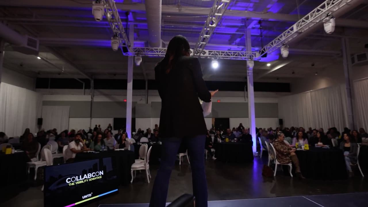 Amy on stage at CollabCon, speaking to a full room
